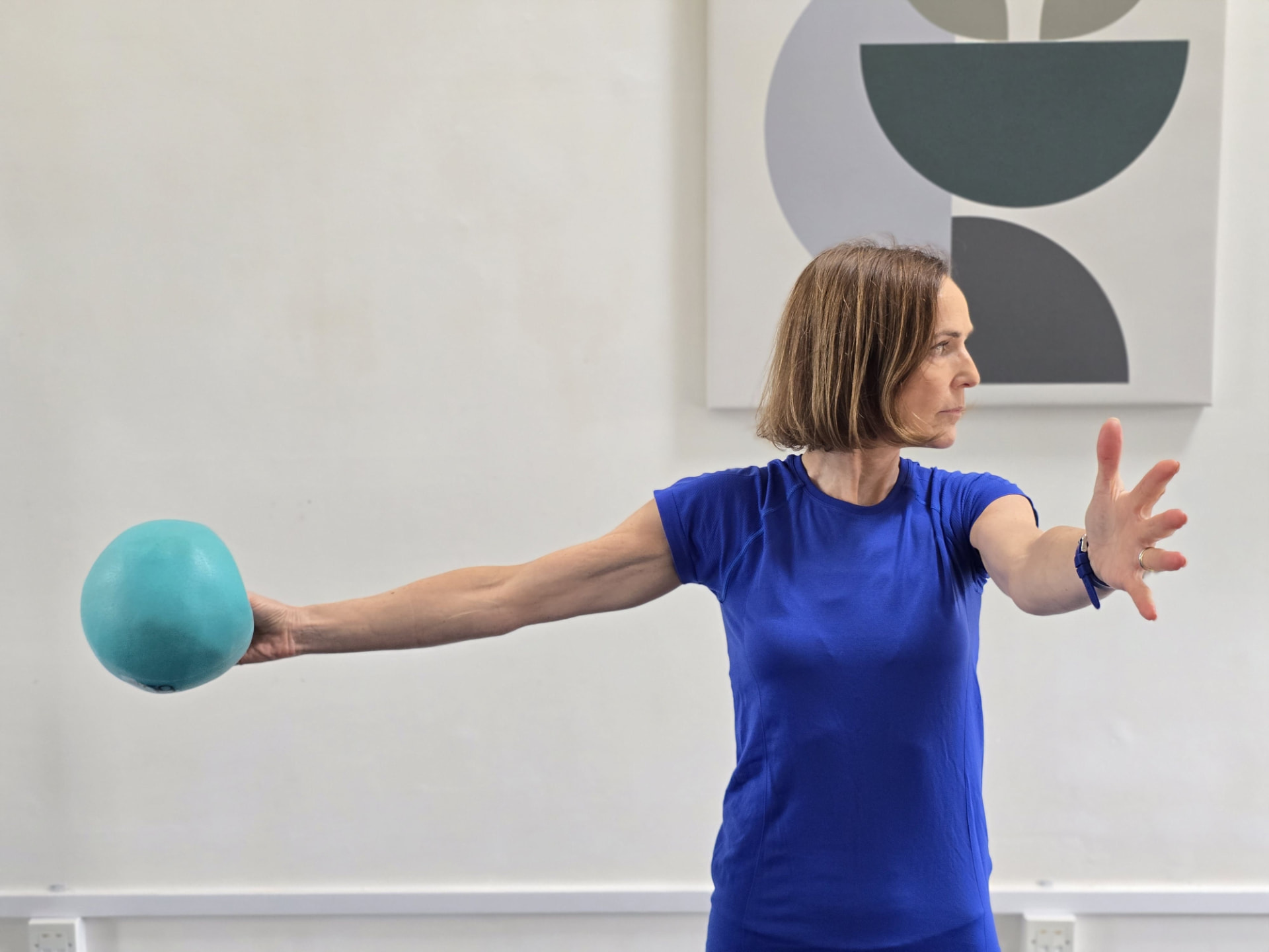 Camilla teaching Pilates with a small weighted ball